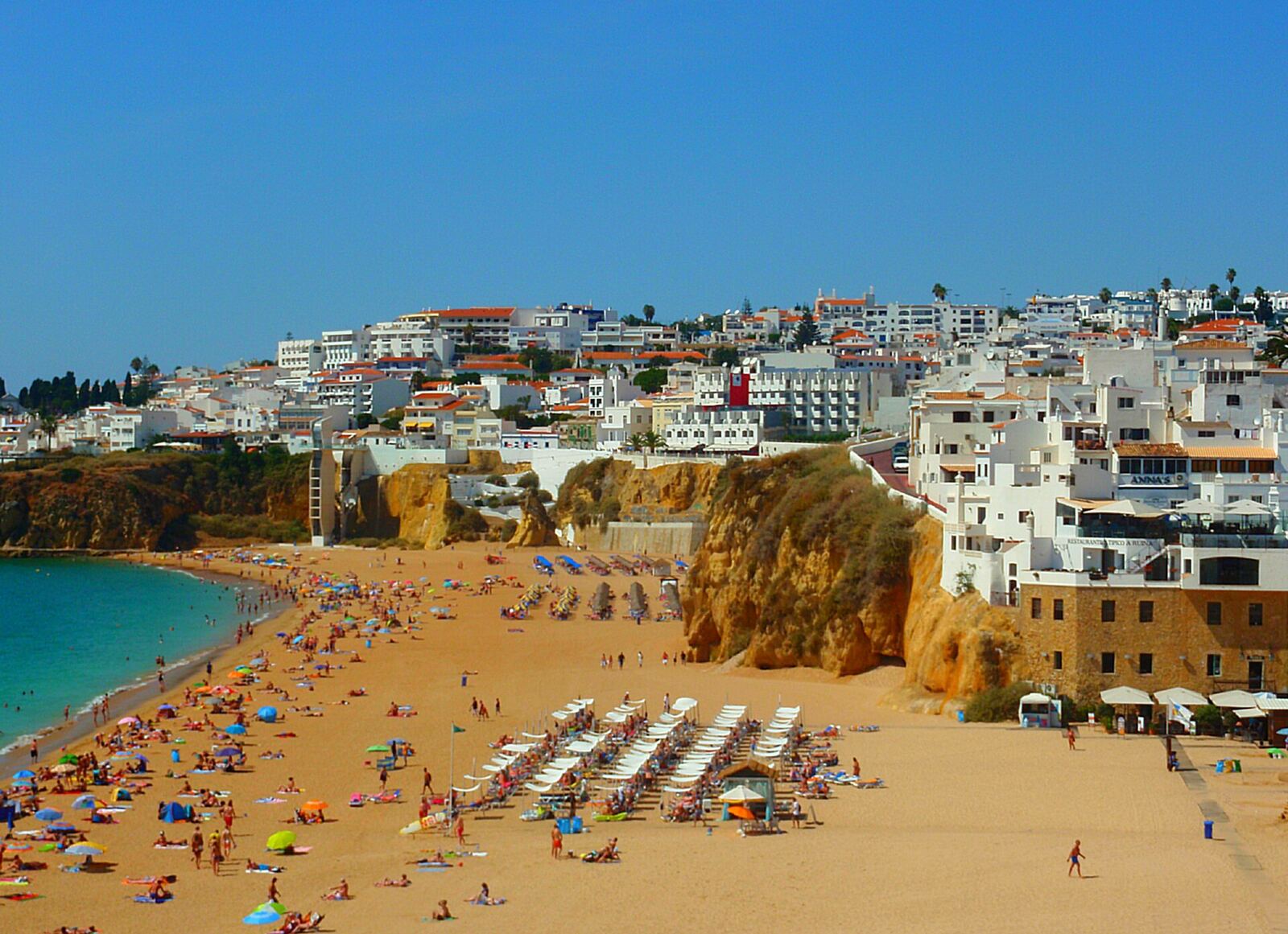 Golden sand beach beside cliffs, with white houses above, in Albufeira