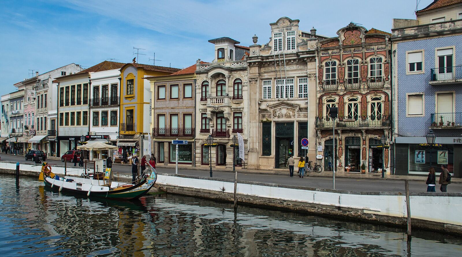 Colourful old houses along a canal, with a traditional boat on the water