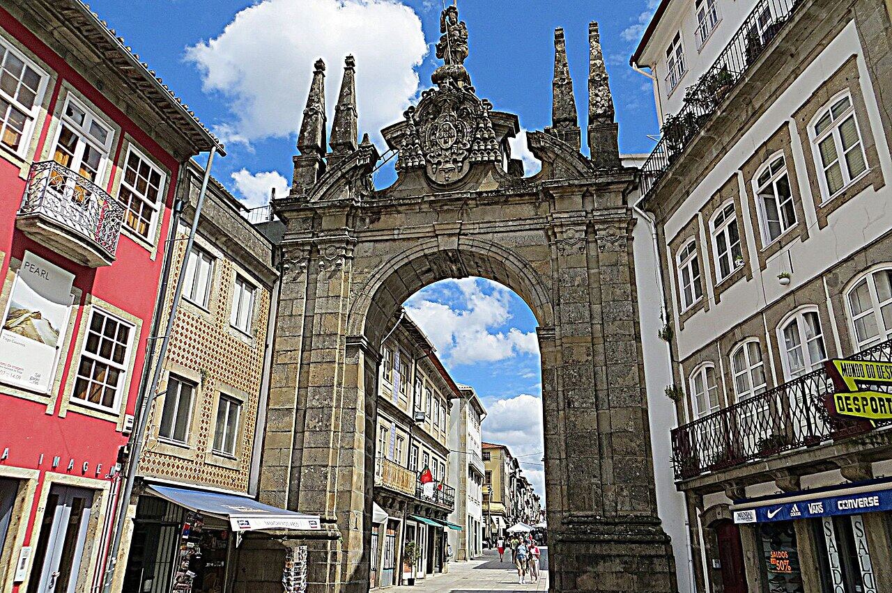 Baroque stone arch, the Porta Nova arch, on a street with colourful houses