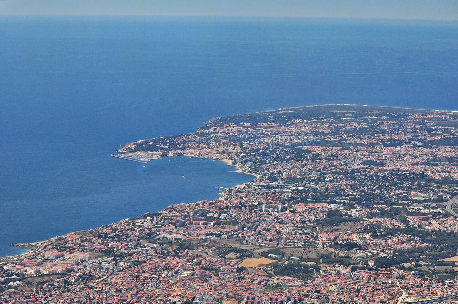 Aerial view of the Cascais coast, with houses beside the blue sea and a bay