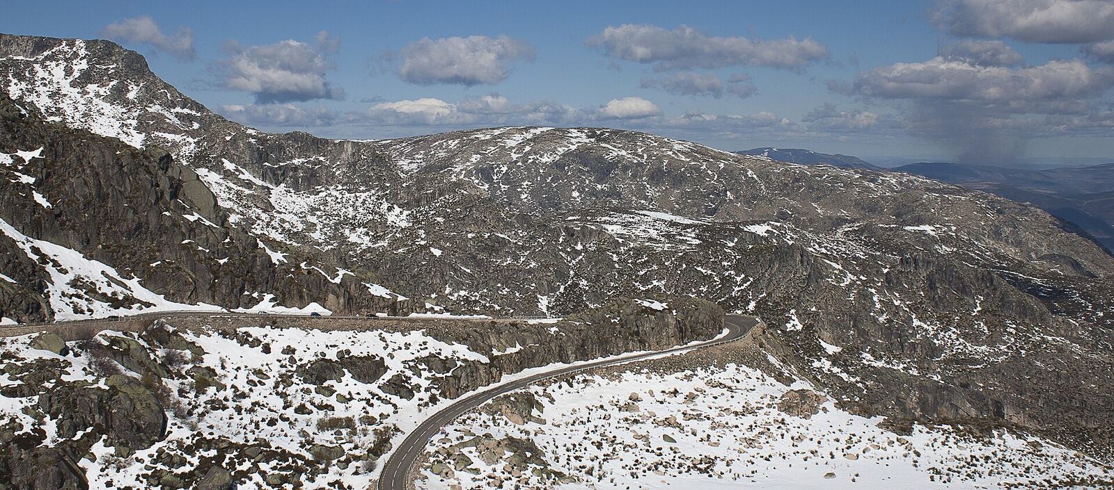 Rocky mountain slopes with snow and a road winding through the landscape
