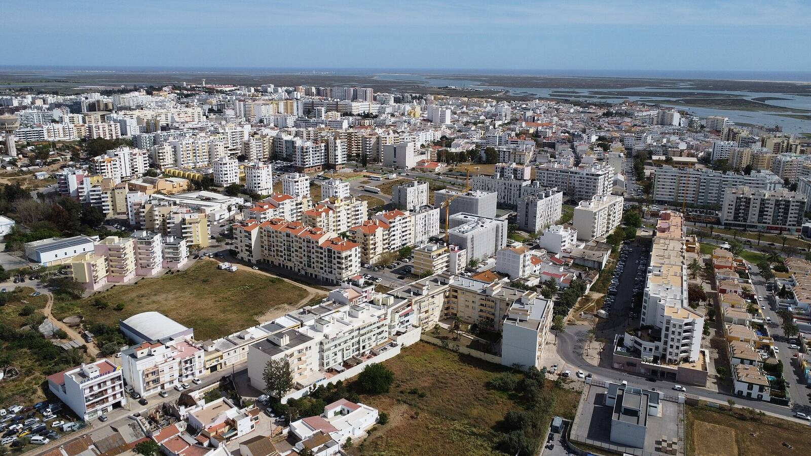 Aerial view of Faro, with white buildings and the Ria Formosa water in the distance