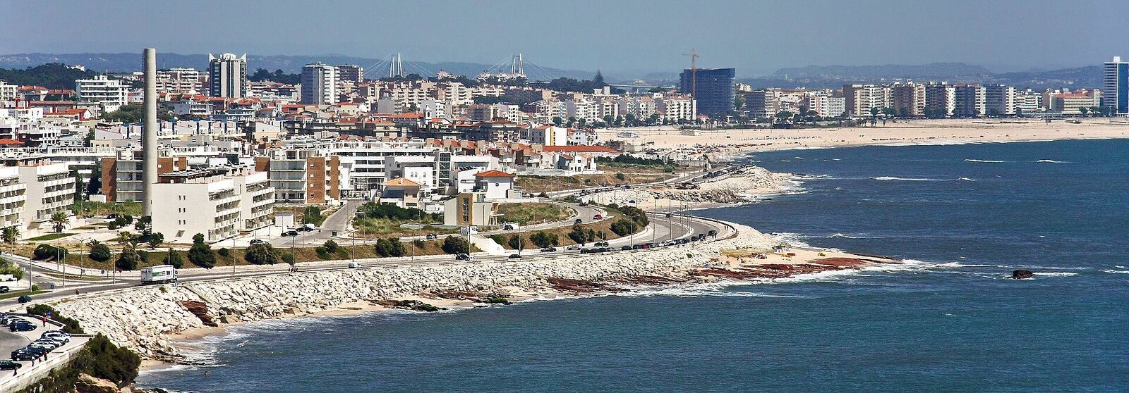 Seaside city with apartment blocks, a rocky shore and the blue ocean seen from above