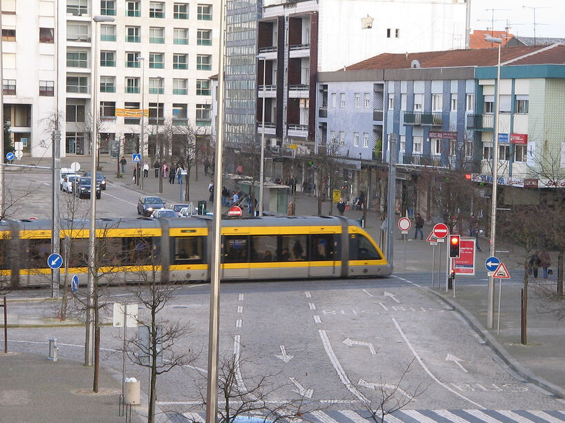Yellow light-rail tram passing along a city street with apartment blocks beside it