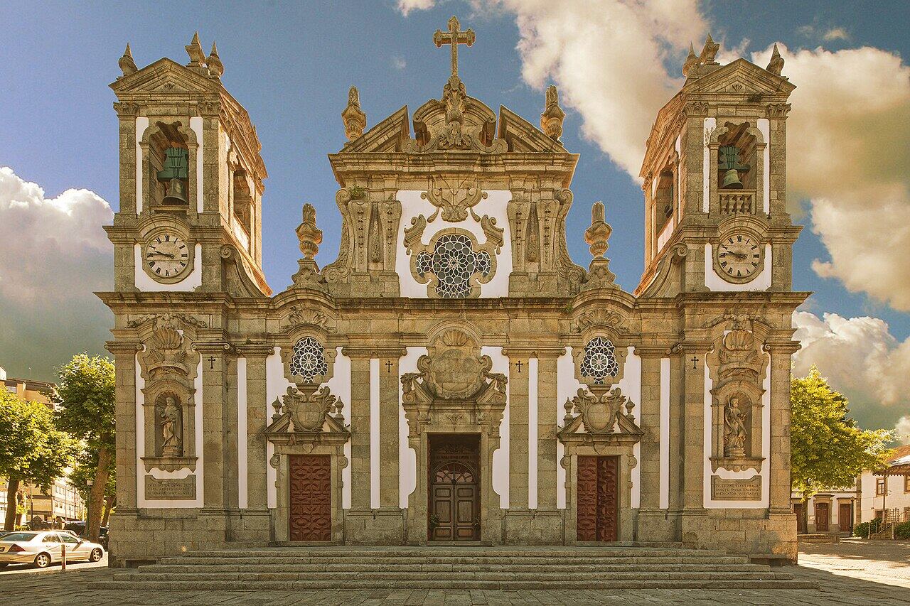 Baroque church with two towers and a white and stone facade, on a square