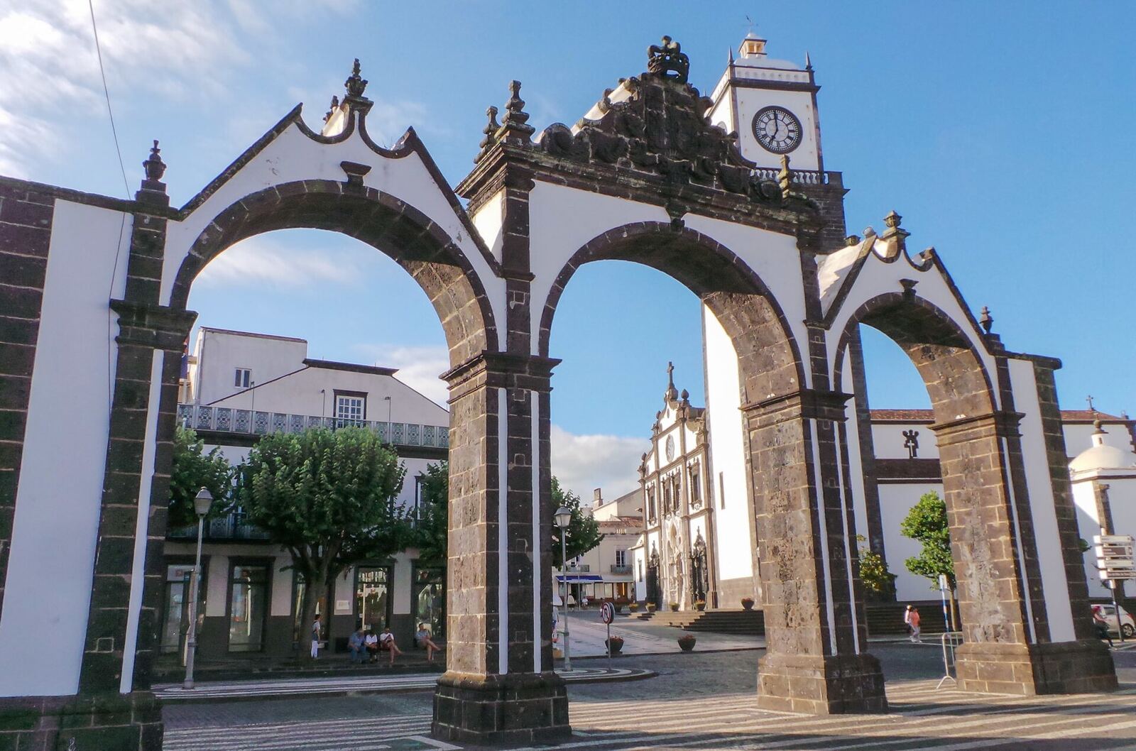 The City Gates of Ponta Delgada: three arches of dark stone and white lime, with the clock tower behind