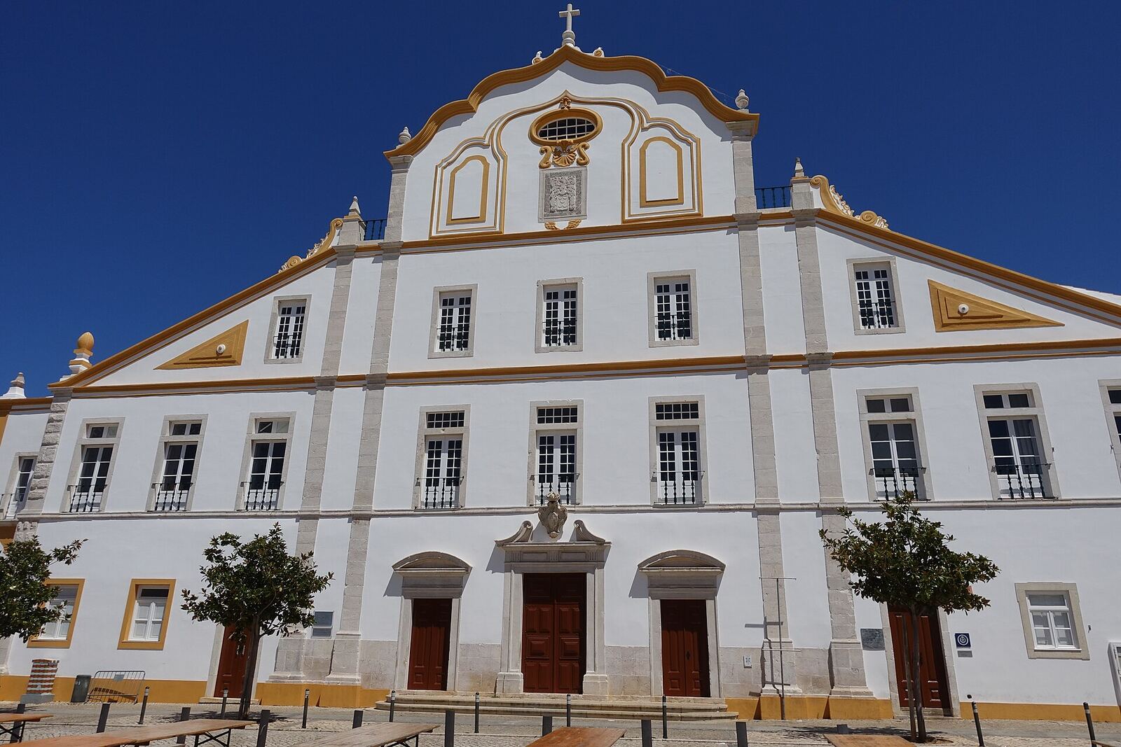 White facade with yellow details of the Jesuit College in Portimão, under a blue sky