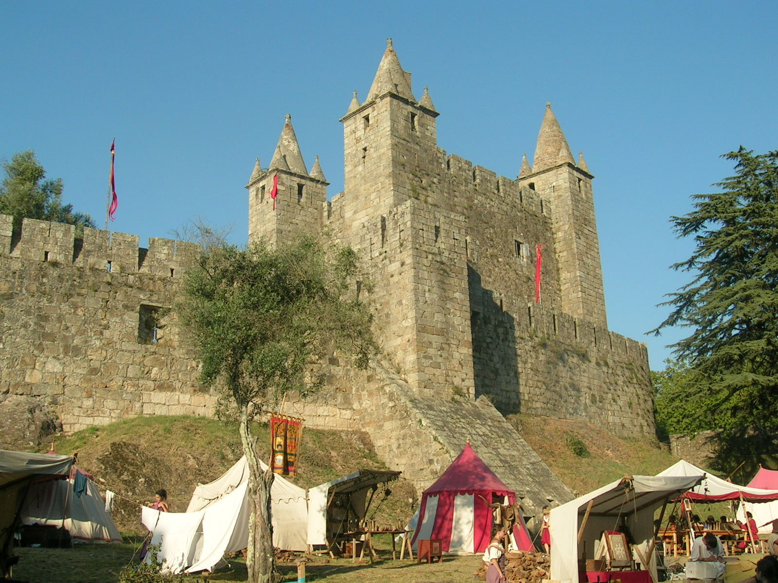 Feira Castle, with the tents of a medieval fair in front, under a blue sky