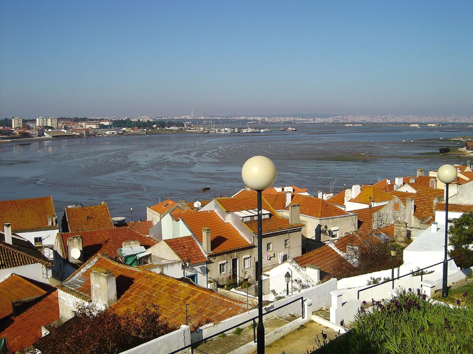 Red rooftops and white walls above a low-tide bay, with the far shore behind