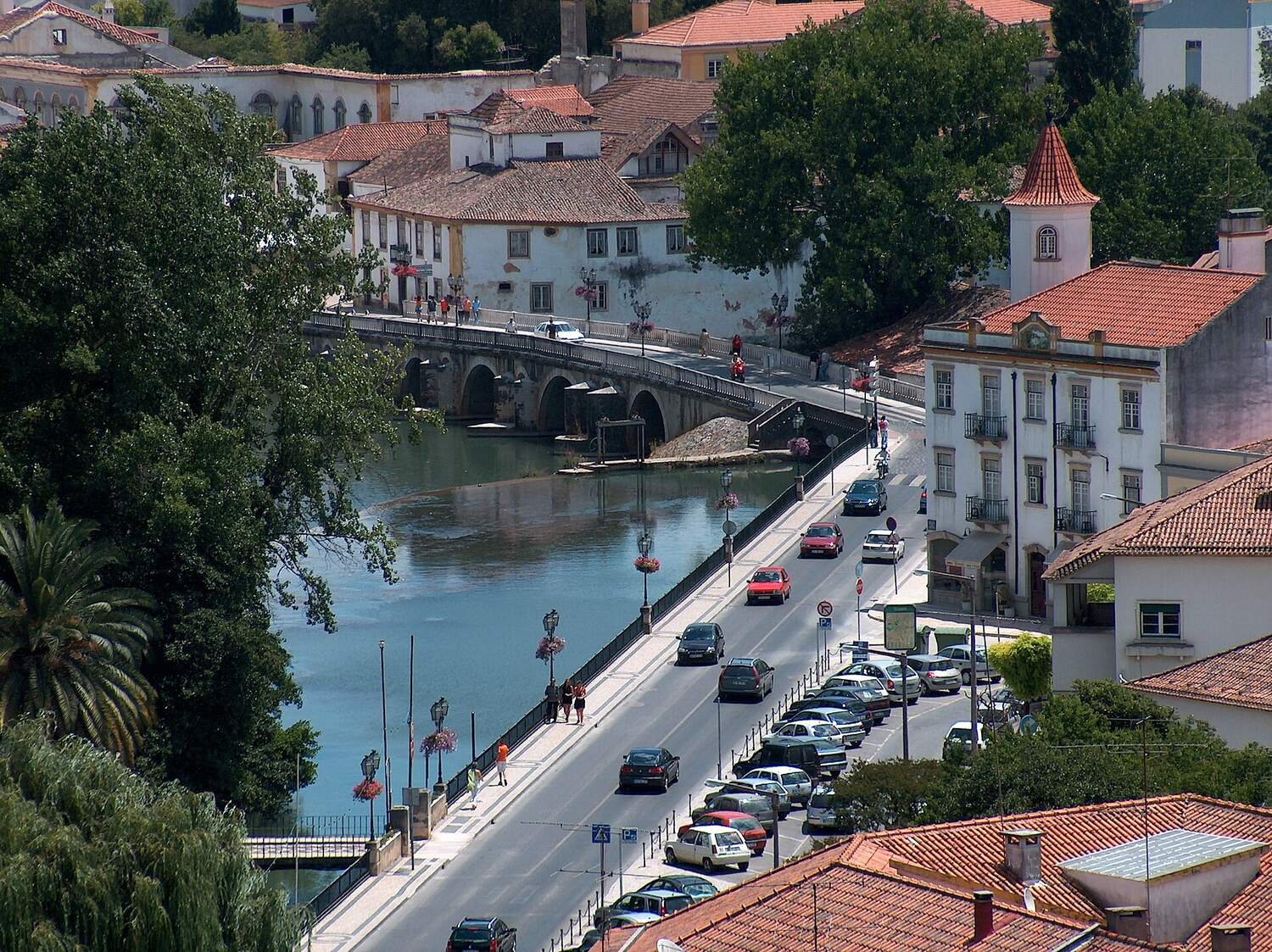 River with an old bridge, a road along the water and red-roofed houses, seen from above