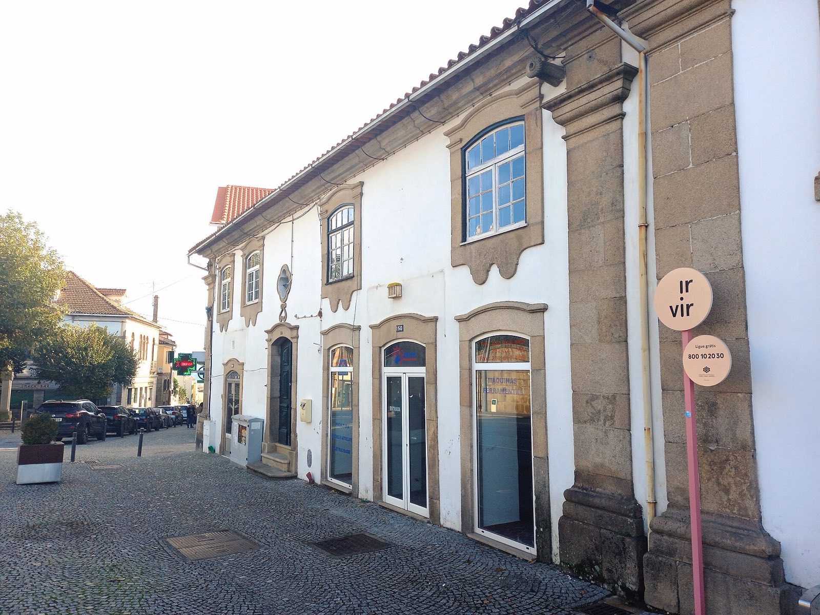 Whitewashed two-storey house with granite frames round the windows and doors, on a cobbled street