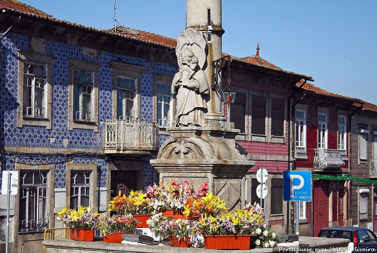Stone cross in a square, with tile-clad houses and flower beds