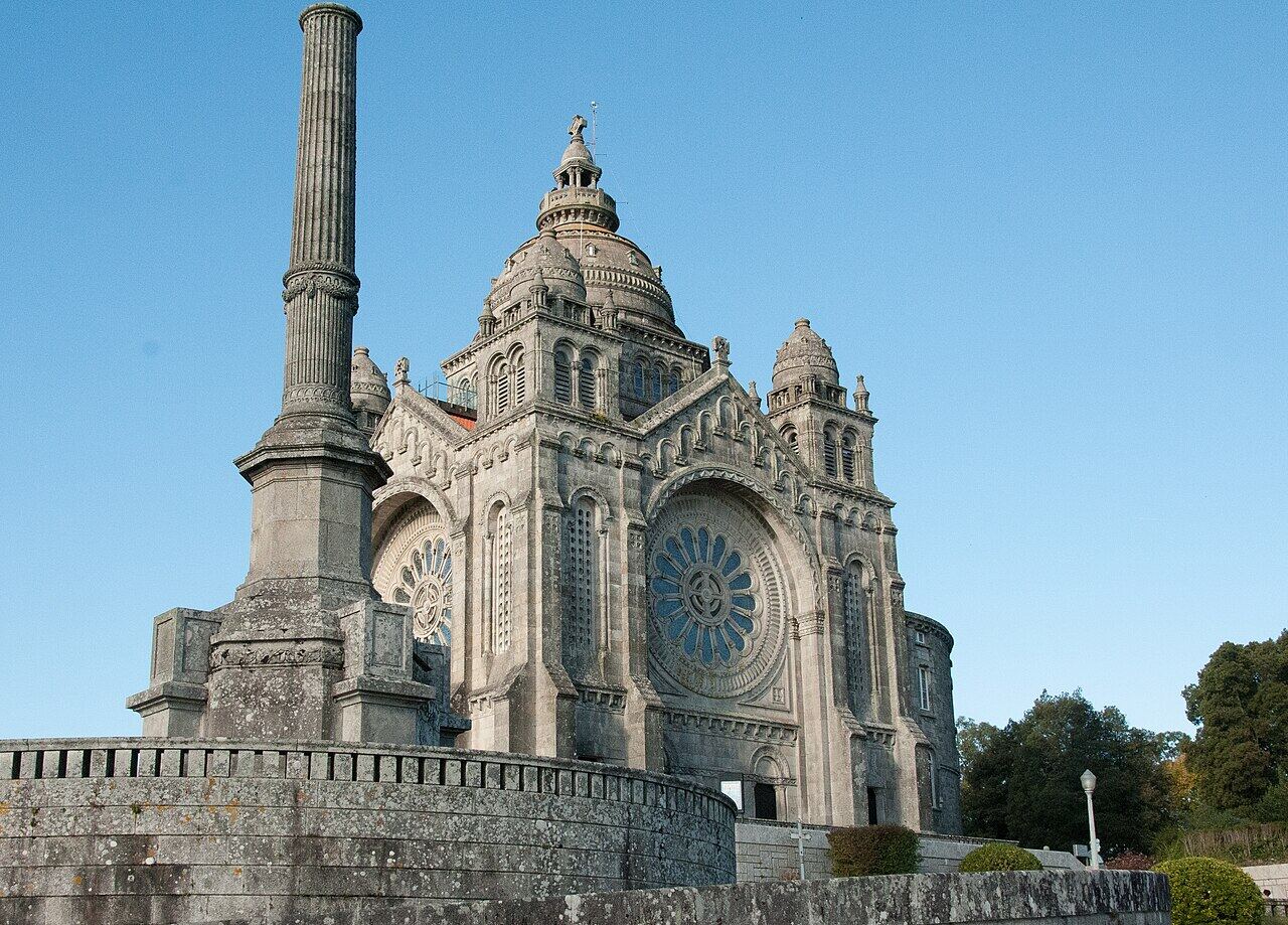 Domed sanctuary with a rose window, on top of a hill, with a stone column beside it